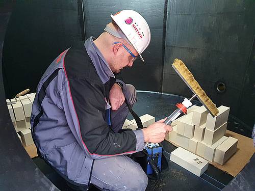 Monteur mit Funkenprüfer im gummierten Quench-Turm