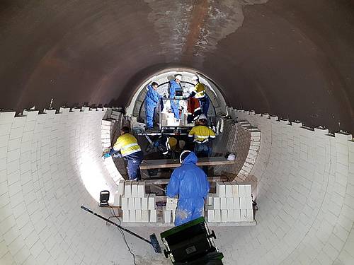 Steuler fitters are lining a rotary kiln with refractory bricks